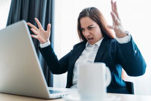 Businesswoman angrily shouts at computer running Windows 7.