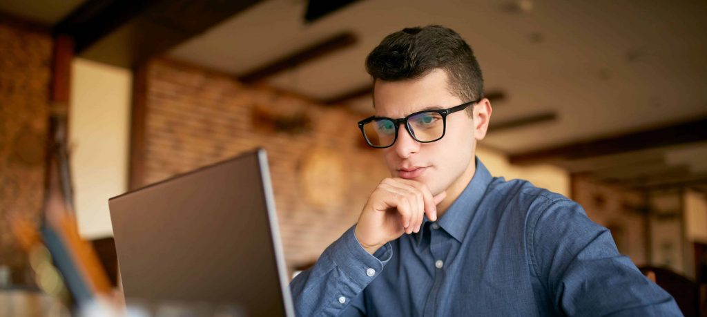 Glasses-wearing man stares at computer, contemplating how to recover hacked files