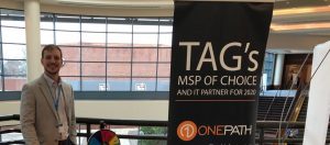 Jon Ulrich smiles behind 1Path booth, happy to be attending the TAG Summit.