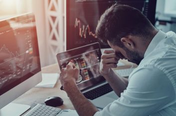 Man slumps over desk looking at negative graphs on a computer, which is why you should be preparing your business for a recession.
